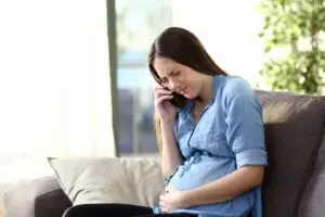 pregnant woman calling doctor sitting on a couch at home