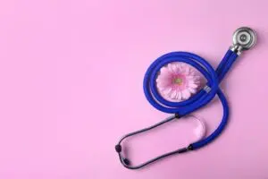 stethoscope and flower on pink background. gynecology concept 