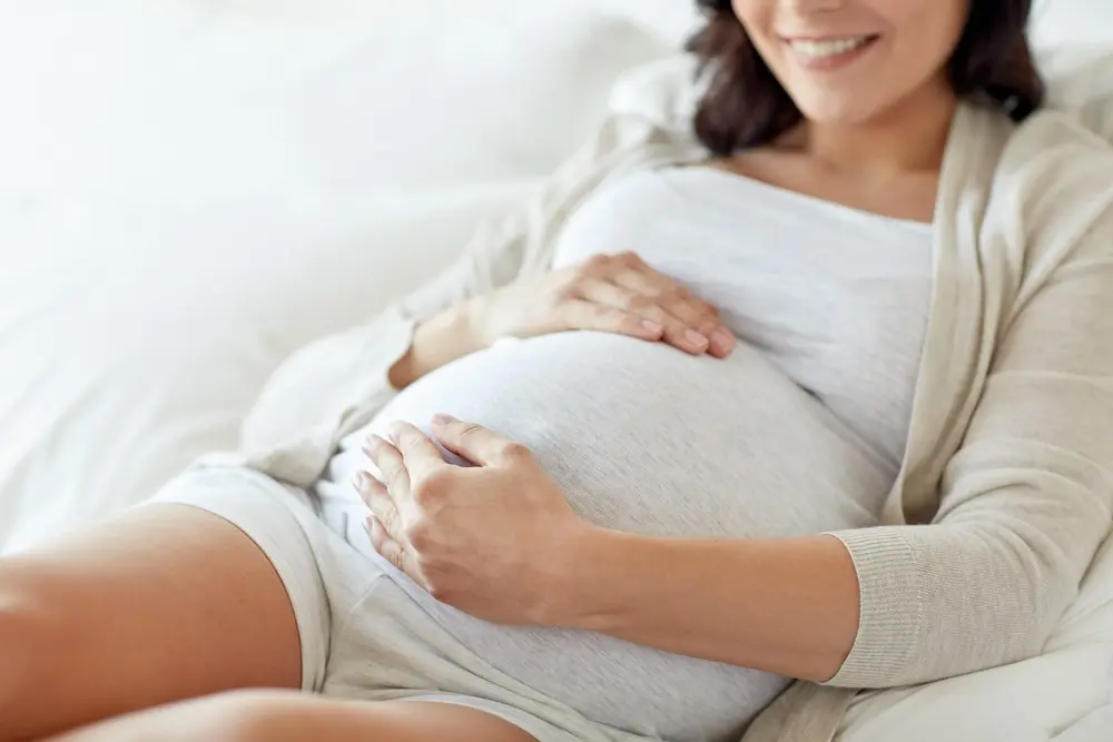 pregnant woman lying in bed and touching her belly