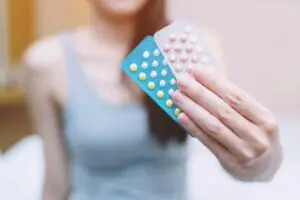 Woman holding up two packs of birth control