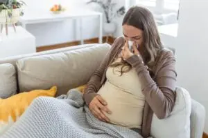 Pregnant woman blowing her nose. 