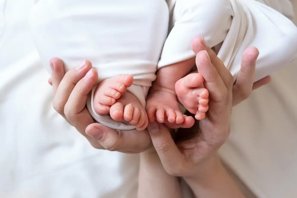 parent holding twin babies feet.