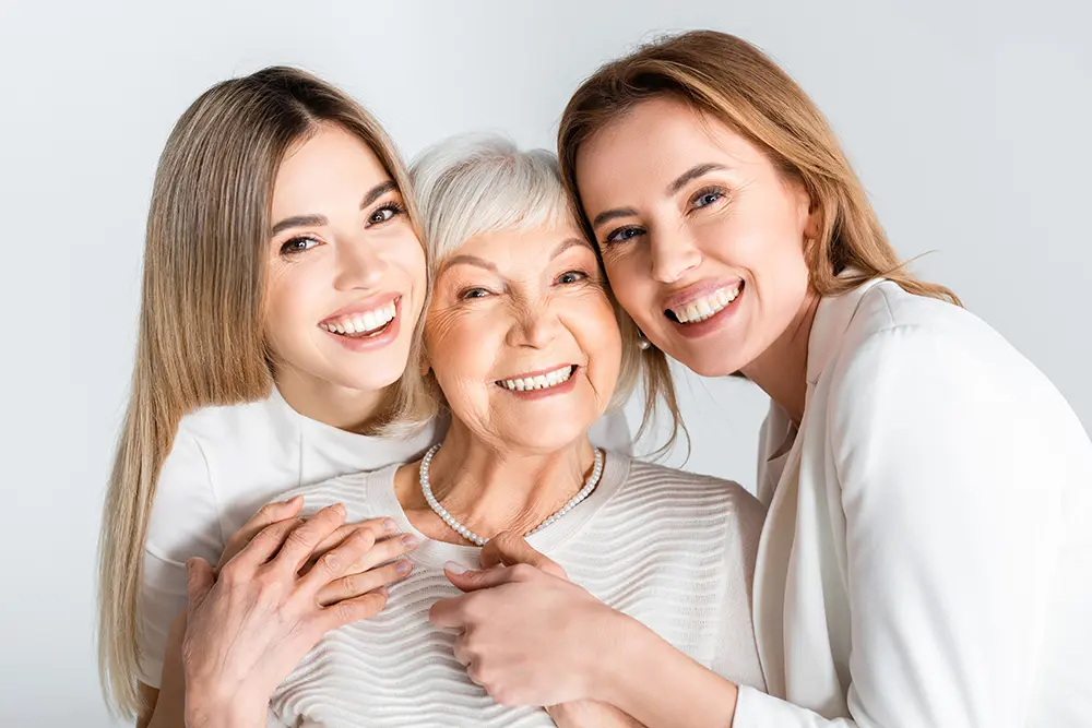 three generation of positive women smiling while looking at camera