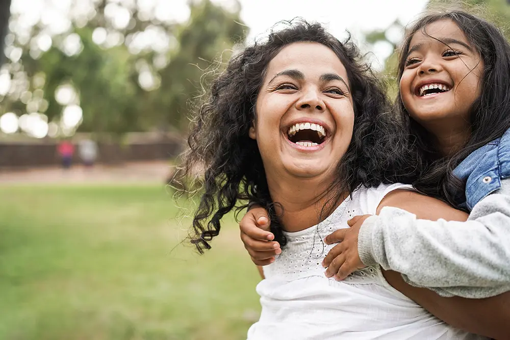 mother giving young daughter a piggy-back ride