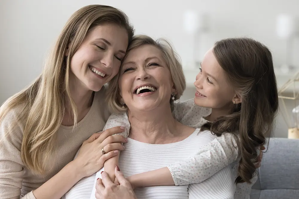 Joyful grandkid girl and adult daughter woman hugging happy grandma