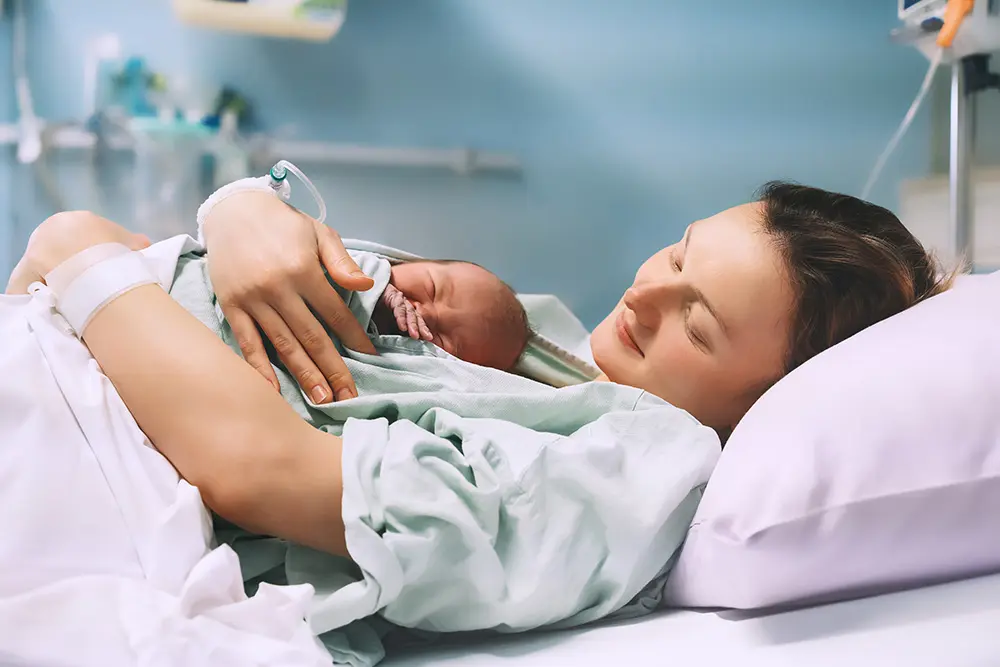 mother laying in hospital bed holding her newborn baby