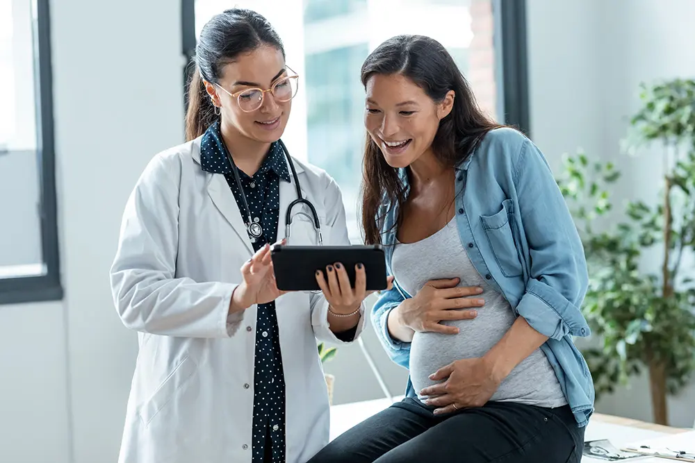 pregnant woman and her doctor looking at a tablet